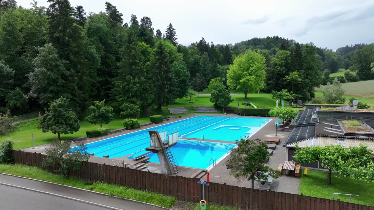 Forladt swimmingpool i smukt naturlandskab. Droneoptagelse fra siden.