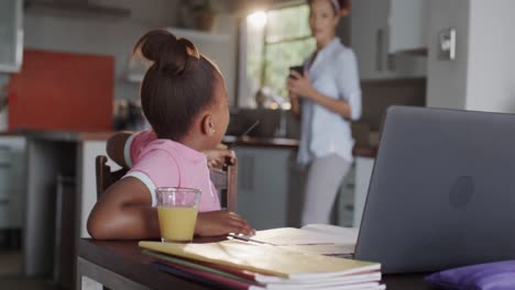 madre y hija afroamericanas felices usando una computadora portátil y haciendo la tarea juntos, cámara lenta