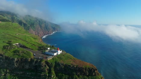 light house on rocky ledge cliff overlooks scenic sweeping views with mystical clouds