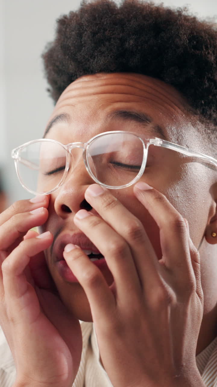 Tired Young Man Rubbing Eyes and Adjusting Glasses