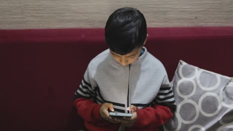 young-kid-watching-mobile-and-playing-online-game-at-home-at-night-from-different-perspective