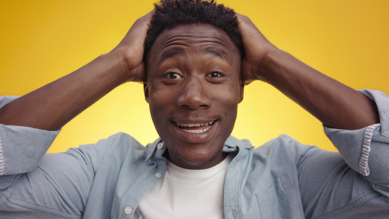 hombre negro con las manos en la cabeza emocionado