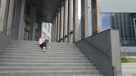 woman working on laptop outdoors on stairs