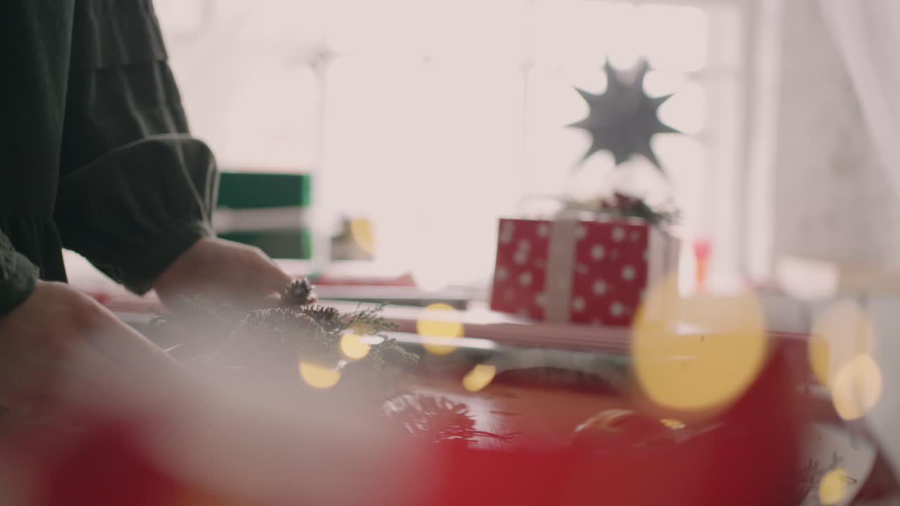 한 젊은 여성의 손이 포장된 선물을 테이블 위로 옮겨 구매자에게 전달합니다. 미리 포장해서 선물을 나눠주다