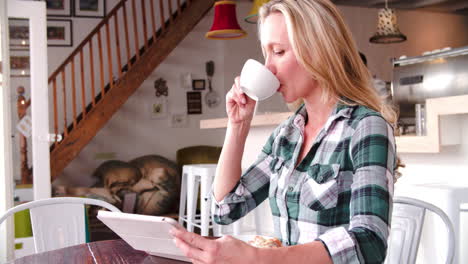 Woman-using-digital-tablet-at-a-table-in-a-cafe