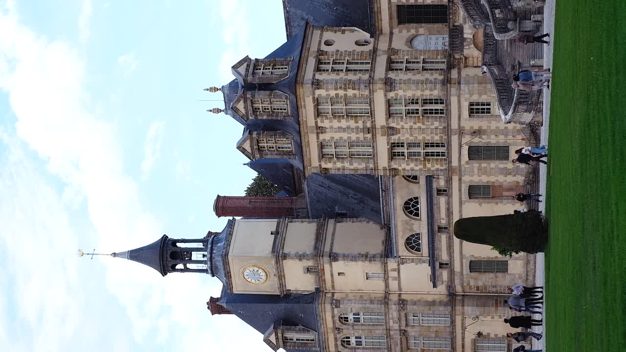 Fontainebleau, France - April 21, 2021: People walking in front of the Chateau de Fontainebleau castle in daylight. Vertical
