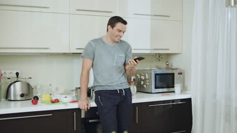 smiling man cooking healthy dinner at home. happy businessman talking phone