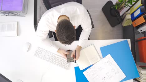 Businessman-working-on-the-project-looks-at-the-phone-and-documents.