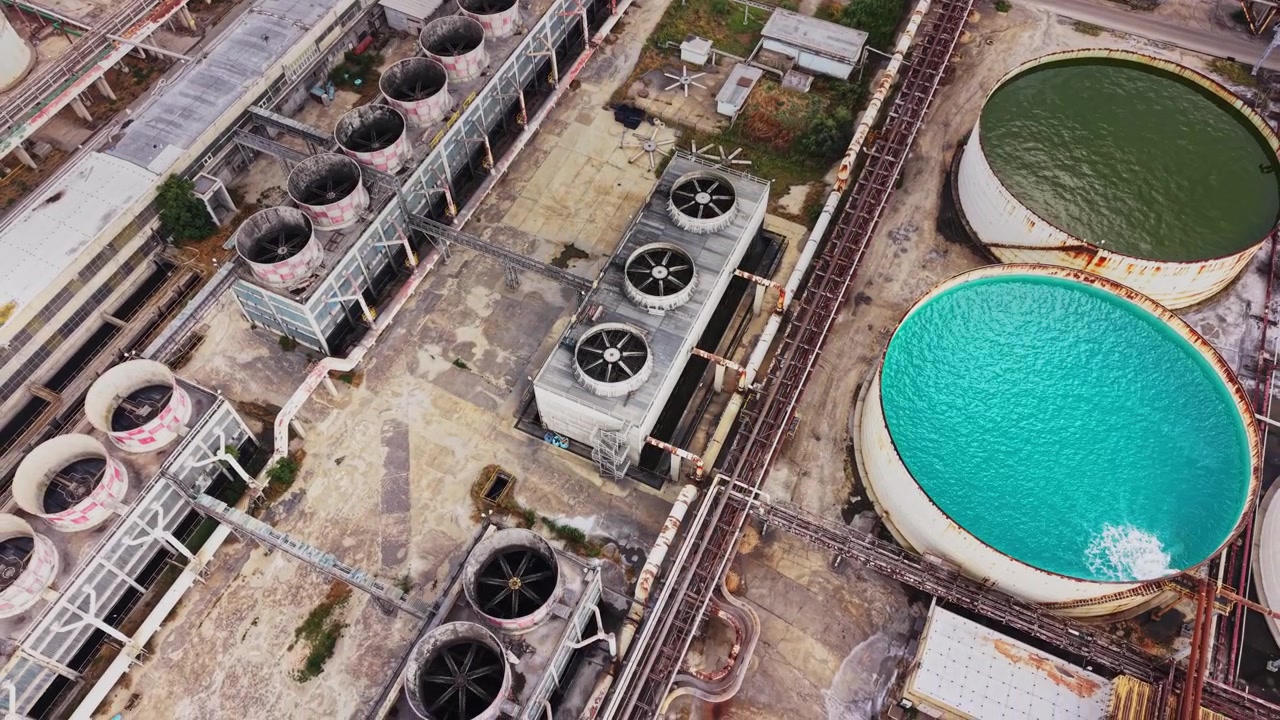 Industrial site with cooling towers and storage tanks in aerial view