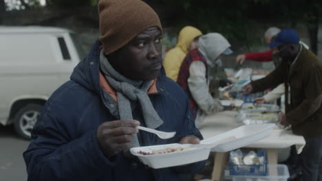 man eating a meal at an outdoor food distribution event