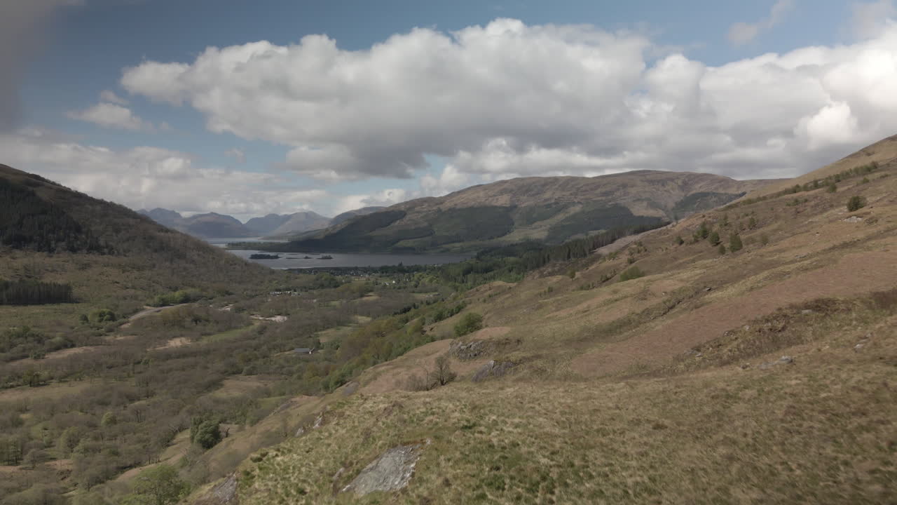 Drone flying forward along side of Scottish mountain on summer day, mountains and sea in the background