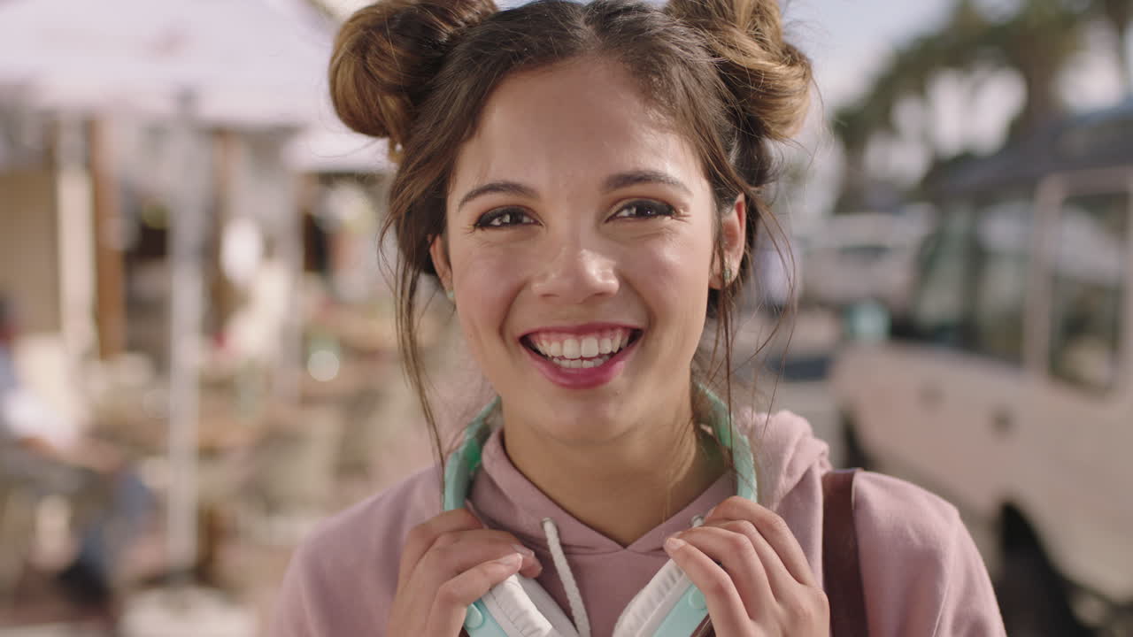 retrato de una joven hermosa mujer hispana sonriendo feliz en una playa soleada con auriculares