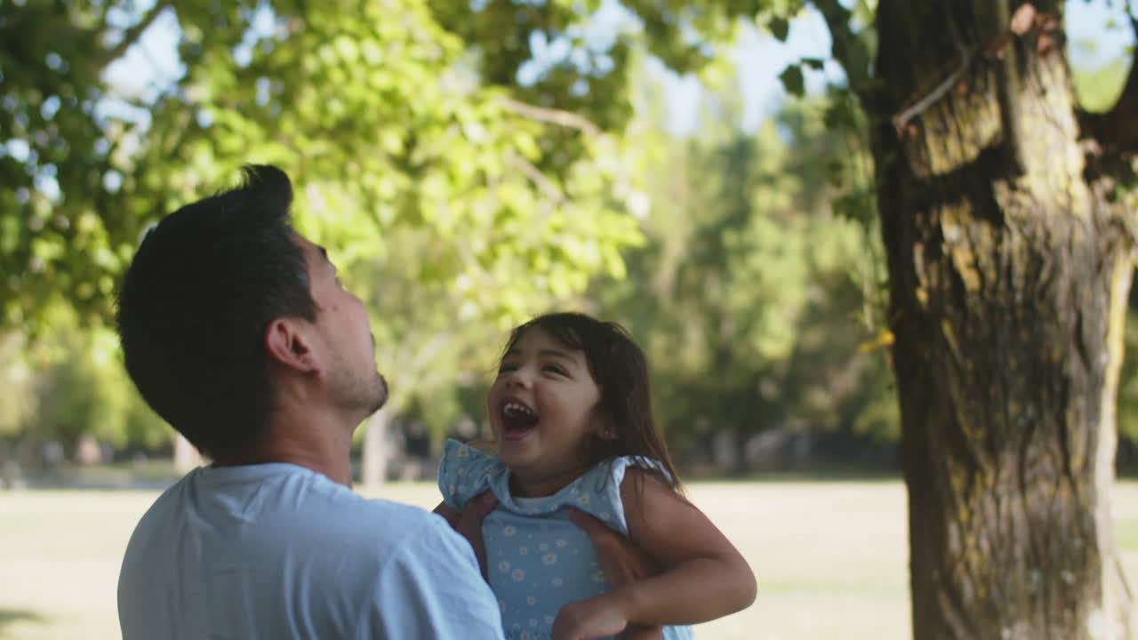 joven asiático lanzando a su linda hijita al aire