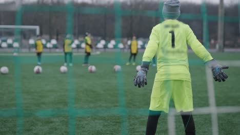 a children's football team trains at the stadium under the guidance of a coach. kids in sports uniforms practice ball exercises, improve technique, and develop teamwork on the green field