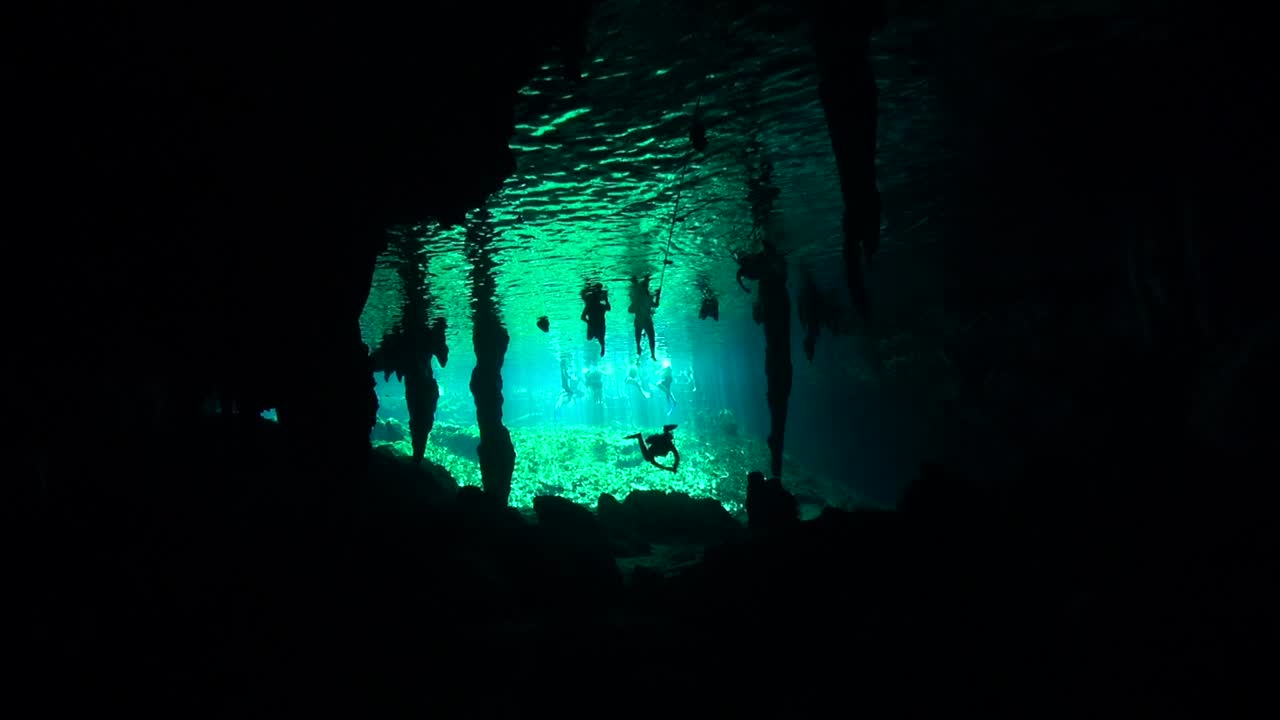 Scuba divers below cenote swimmers