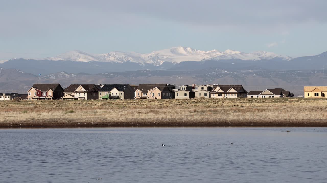 жилой комплекс с озером на переднем плане и скалистыми горами на заднем плане