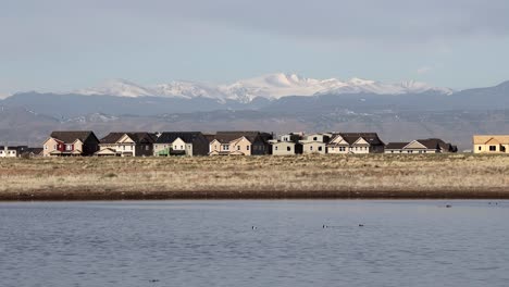 housing development with lake in the foreground and rocky mountains in the background