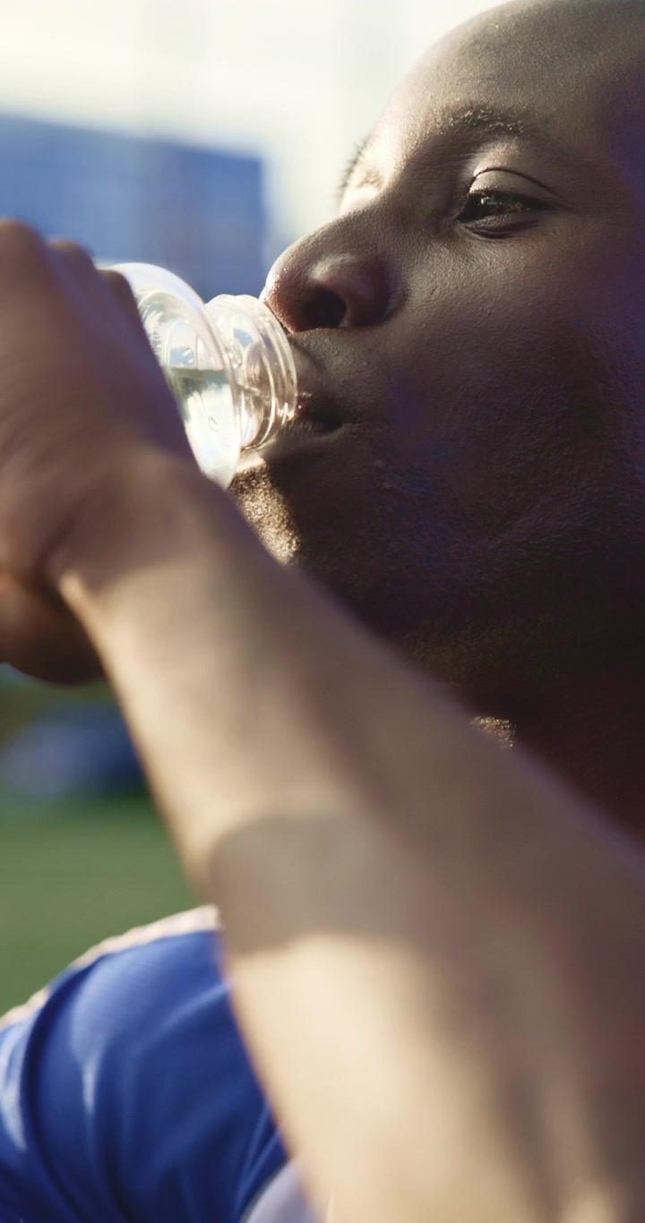 Young Athlete Drinking Water After Training Outdoors