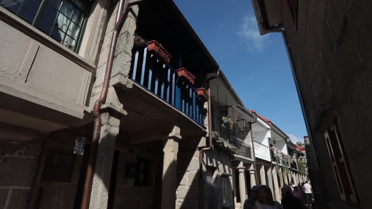 Narrow street view of historic stone buildings under a clear blue sky in Pontevedra, Spain