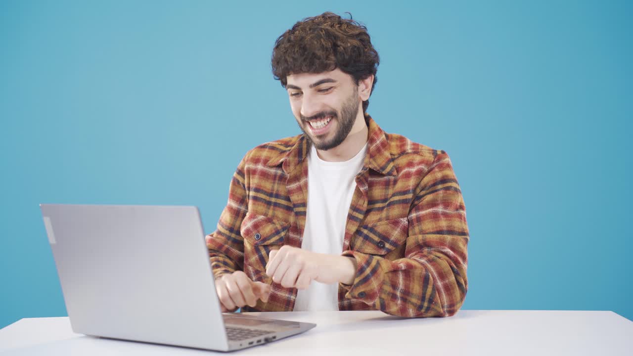 un joven guapo con el cabello rizado usando una computadora portátil.