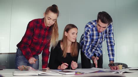 un grupo de diseñadores de interiores trabajando juntos en la oficina. jóvenes hipsters haciendo bocetos de pie en la mesa y