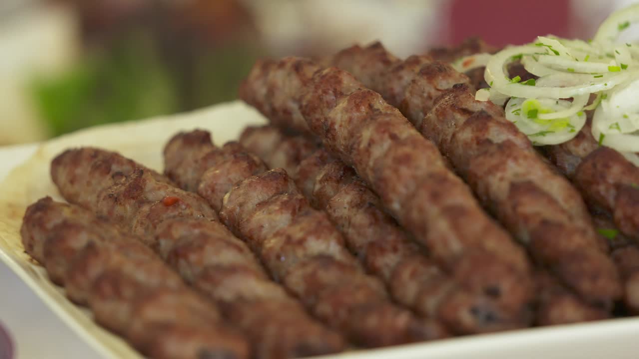 Lula kebabı ve taze sebzelerle servis edilen yemek masası