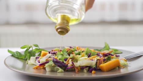 healthy lifestyle. pouring olive oil on the salad.