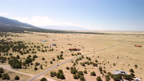white suv leaving the mountains and driving into the plains of colorado, aerial side view