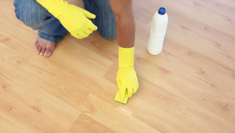 Man-cleaning-floor-with-sponge