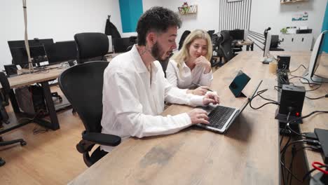 Coworkers collaborating on laptop in modern office