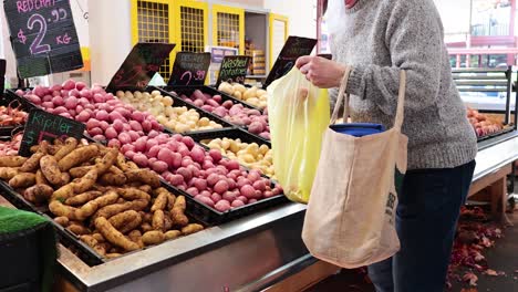 person picking potatoes at a market stall