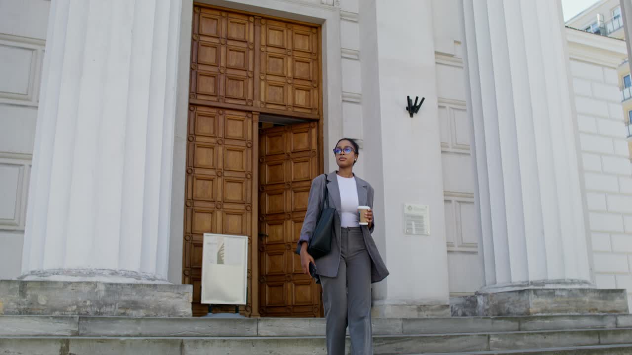 una mujer de negocios subiendo las escaleras frente a un edificio.