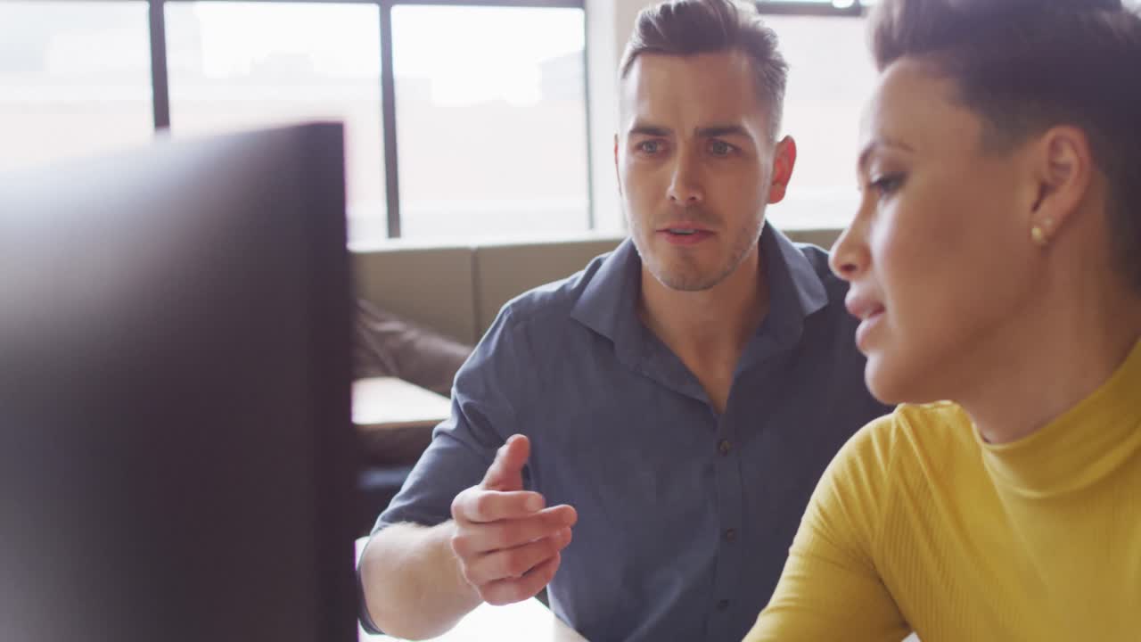 personas de negocios caucásicas felices sentadas a la mesa y discutiendo el trabajo en la oficina