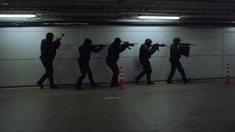 swat police officers walking on parking. special forces aiming assault rifles