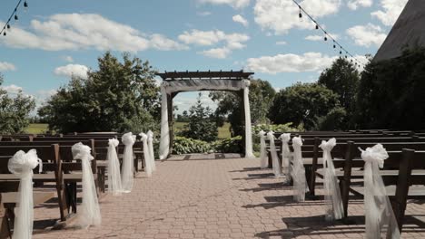 Caminando-Por-La-Isla-De-Una-Hermosa-Ceremonia-De-Boda-En-Un-Patio-Al-Aire-Libre