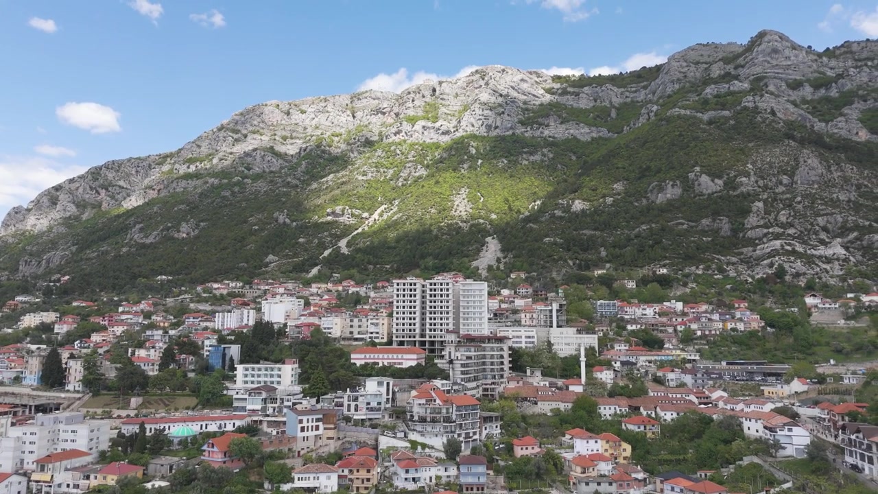 Aerea - Città collinare di Kruja, Albania, con tetti rossi, condomini e montagna calcarea