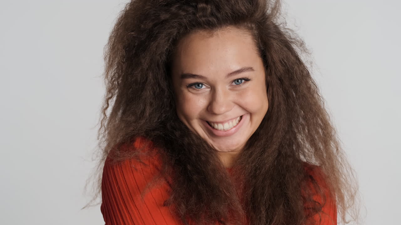 una mujer caucásica de cabello rizado enviando un beso a camara.