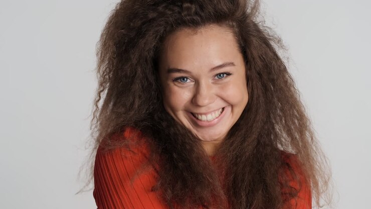 Caucasian curly haired woman sending a kiss to camara.