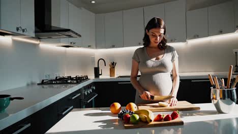 pregnant woman preparing a fruit salad in a modern kitchen