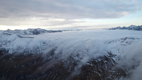 Epische-4K-Luftaufnahme-Niedriger-Wolken,-Die-Die-Hohen-Schneebedeckten-Berggipfel-Österreichs-Bedecken