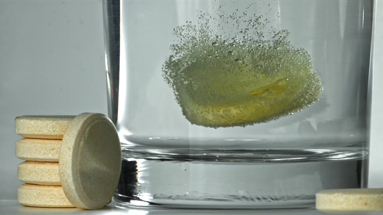 Yellow Effervescent Tablet Dissolving in a Glass of Water