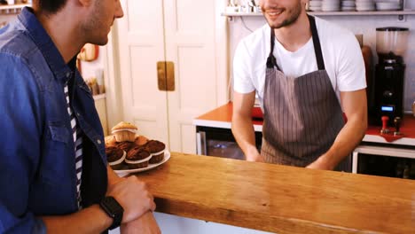 waiter giving coffee to young customer at counter