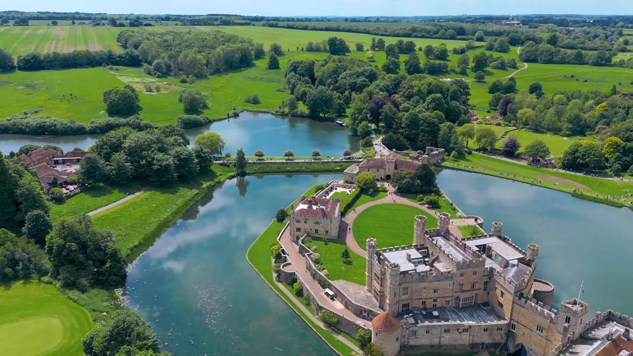 Aerial View of a Stunning Castle Surrounded by Water and Lush Greenery