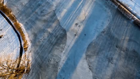 fast drone flying above a frozen pond in michigan during sunset