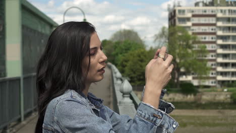 Attraktive-Latina-Touristin-Konzentriert-Sich,-Während-Sie-Von-Einer-Brücke-Aus-Ein-Foto-Von-London-Macht-Und-Dabei-Ihr-Telefon-In-Der-Hand-Hält,-Um-Das-Bild-Einzurahmen