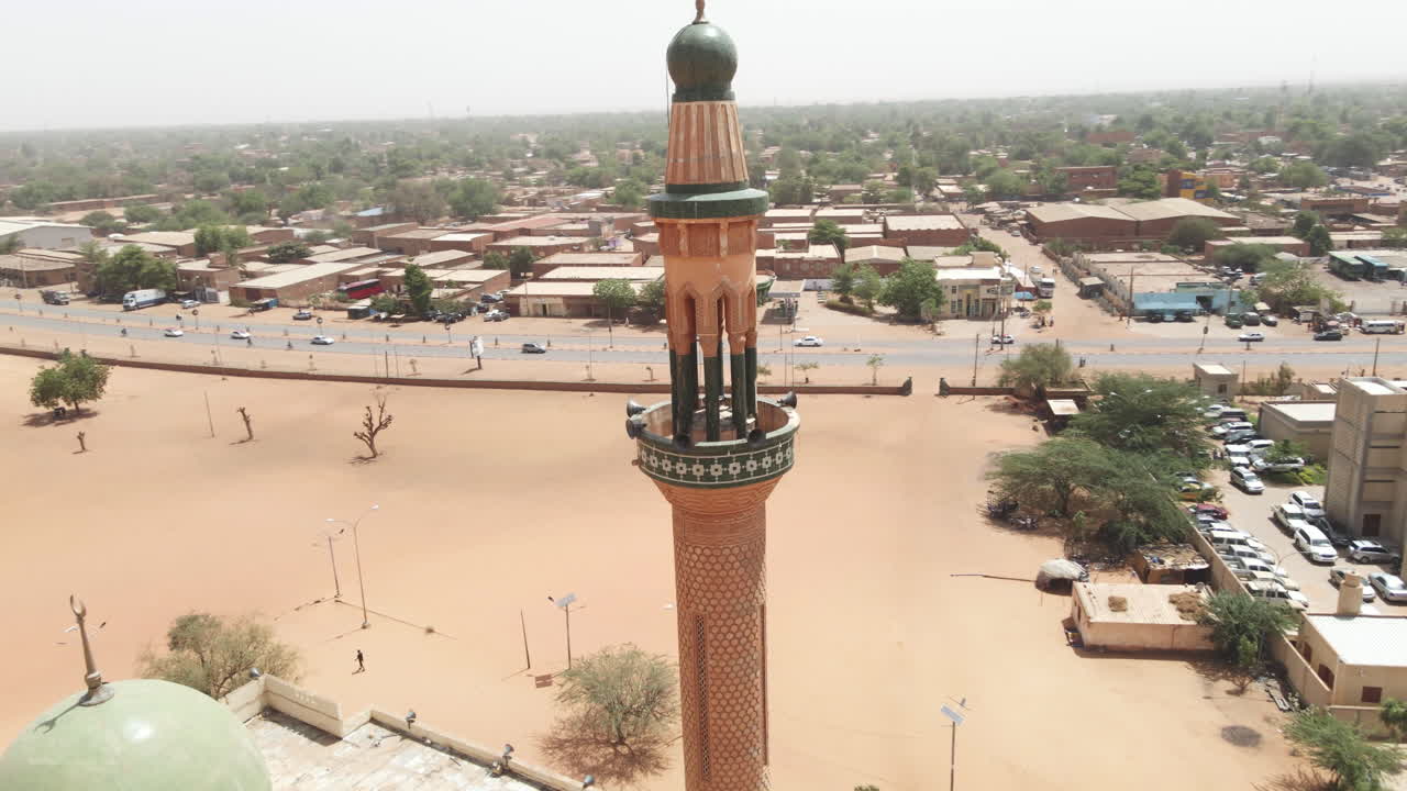 In Nigeria, a daytime drone spirals forward over a mosque, gradually revealing the surrounding urban layout and cityscape