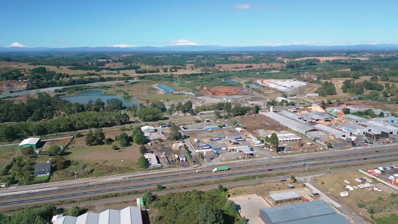Panorâmica sobre uma área industrial com armazéns e lagos em paisagem rural.