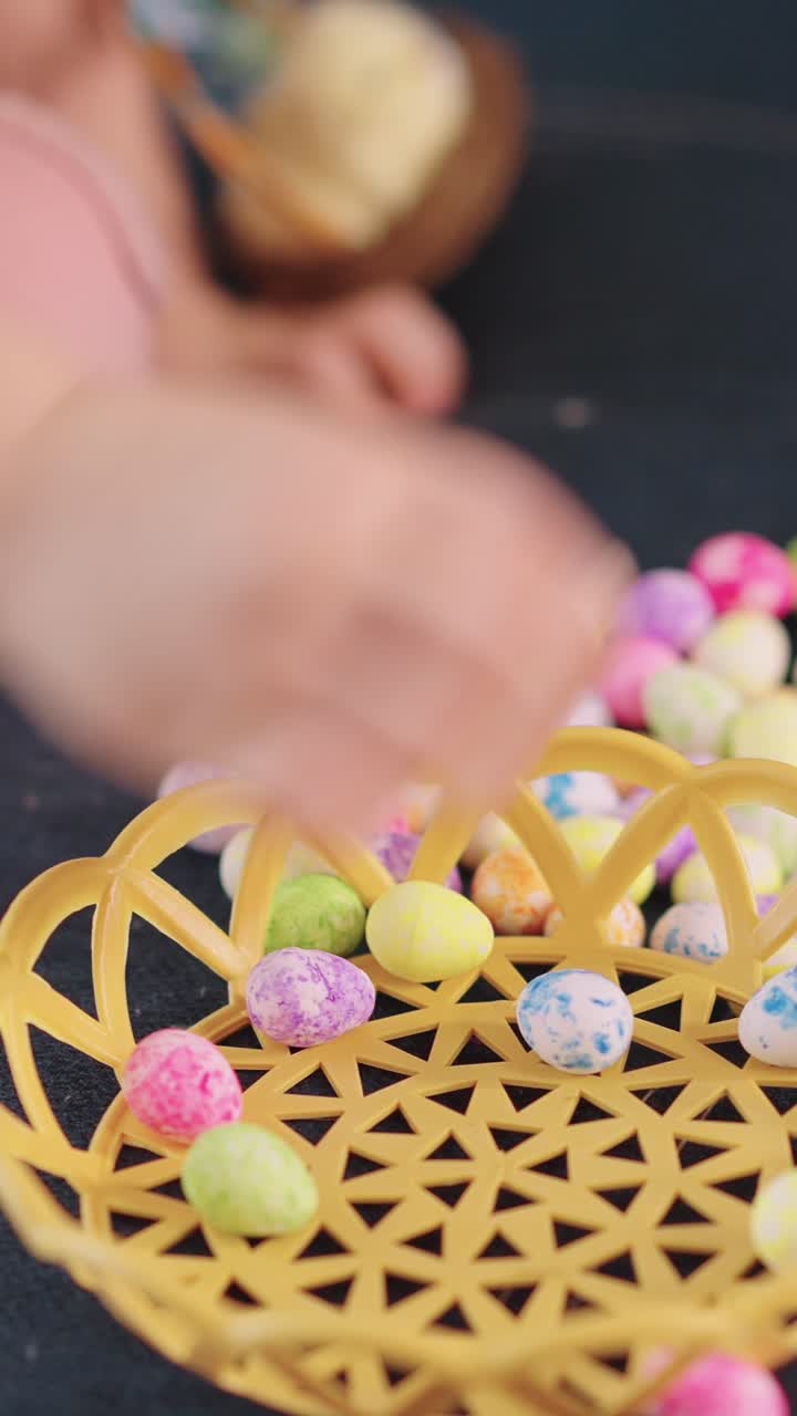 Child's Hand Placing Colorful Mini Easter Eggs into a Basket