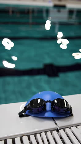 swimming goggles and cap by the pool