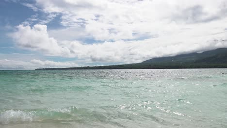 Cerca-De-Olas-Con-Palmeras-Cubiertas-De-Isla-Paradisíaca-En-El-Océano-Pacífico-Con-Nubes-Blancas-Y-Esponjosas-Y-Cielo-Azul